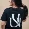 Femme souriante portant un t-shirt noir UNIVESCO avec grand logo au dos